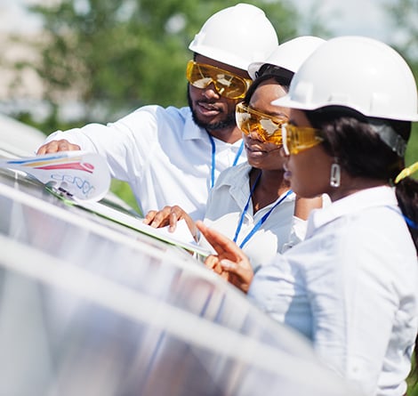 Drei Ingenieure prüfen die Konstruktionsunterlagen für ein System zur Gewinnung von Solarenergie.