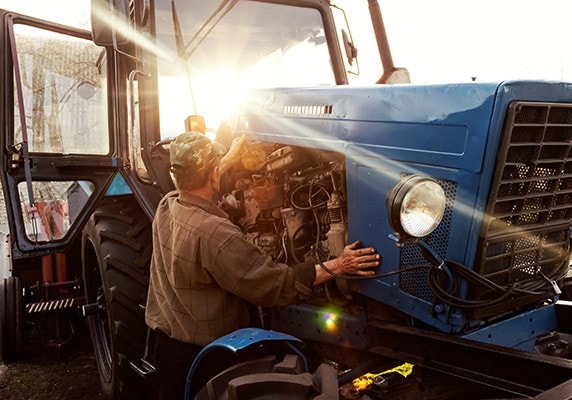 A mechanic repairs a farm tractor.